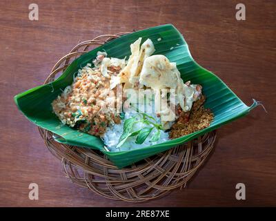 Pecel Pincuk, un cibo tradizionale giavanese, servito su foglie di banana, uno dei pacchetti alimentari ecologici. Foto Stock