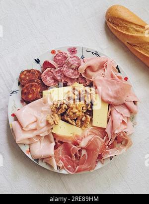 Vista dall'alto di un piatto di prosciutto assortito, salame, formaggio e noci con una baguette Foto Stock