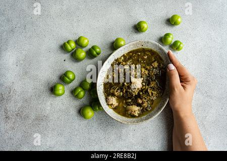 Piatto tradizionale georgiano stagionale Chakapuli servito nella ciotola su un tavolo di cemento Foto Stock