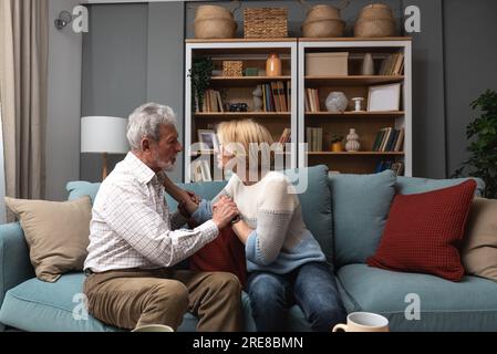 Coppia anziana, colloquio serio e comunicazione circa i problemi e le edizioni di Unione mentre sedendosi sul divano nel paese. Uomo e donna maturi che parlano e d Foto Stock