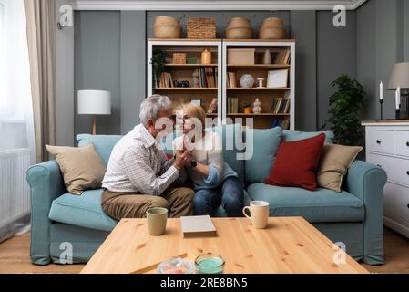 Coppia anziana, colloquio serio e comunicazione circa i problemi e le edizioni di Unione mentre sedendosi sul divano nel paese. Uomo e donna maturi che parlano e d Foto Stock