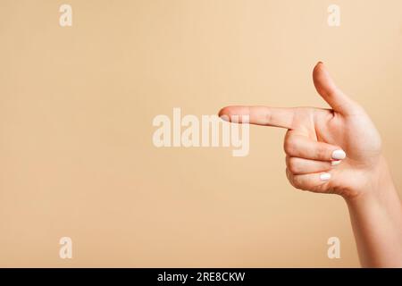 indice che punta in una posizione, sfondo beige con spazio per la copia Foto Stock