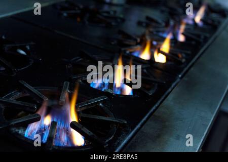 5 bruciatori a gas illuminati nella cucina di un ristorante Foto Stock