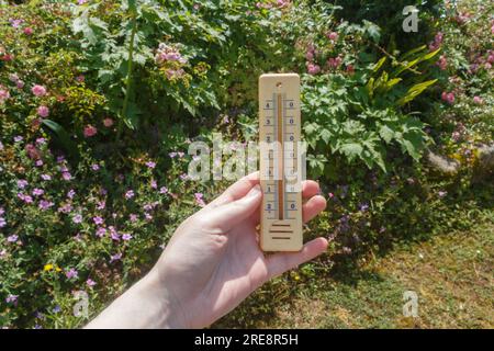 Termometro nelle mani di una donna in un giardino Foto Stock