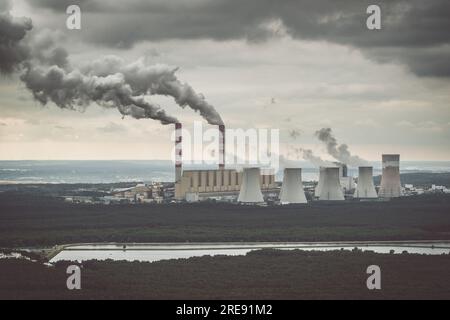 Vista aerea della centrale elettrica, fumo dai camini e miniera di carbone a cielo aperto a Belchatow sotto un cielo nuvoloso, Polonia Foto Stock