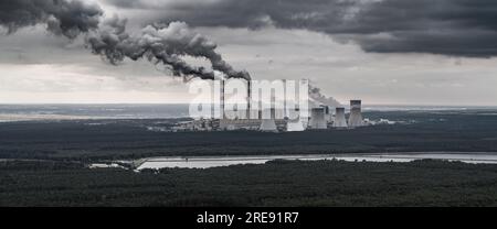 Vista aerea della centrale elettrica, fumo dai camini e miniera di carbone a cielo aperto a Belchatow sotto un cielo nuvoloso, Polonia Foto Stock