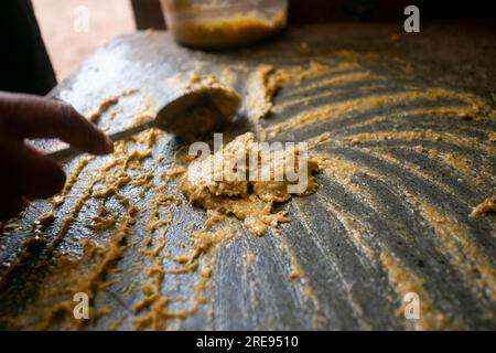 Preparazione del peperoncino giallo peruviano, chiamato anche salsa aji amarillo con un mulino nella città di Cusco in Perù. Foto Stock