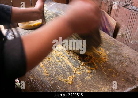 Preparazione del peperoncino giallo peruviano, chiamato anche salsa aji amarillo con un mulino nella città di Cusco in Perù. Foto Stock