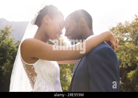 Felice sposo e sposo afroamericano che si sposa al matrimonio nel soleggiato giardino Foto Stock