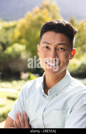 Ritratto di un uomo asiatico felice sorridente in un giardino soleggiato. Benessere, estate, tempo libero, natura e stile di vita, inalterati. Foto Stock