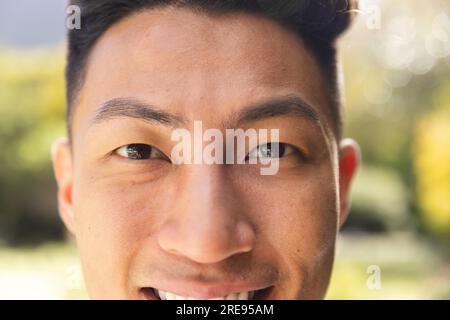 Ritratto ravvicinato di un uomo asiatico felice sorridente in un giardino soleggiato Foto Stock