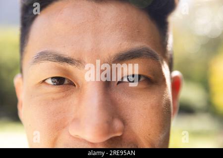 Ritratto ravvicinato di un uomo asiatico felice sorridente in un giardino soleggiato Foto Stock