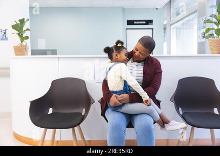 Felice madre e figlia afroamericana seduti in sala d'attesa all'ospedale, spazio fotocopie Foto Stock
