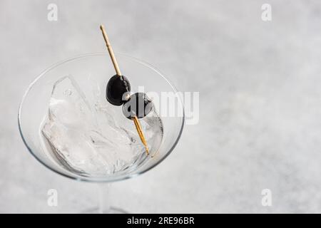 Dall'alto bicchiere riempito con alcol martini vodka cocktail con olive nere in vetro martini su tavolo di cemento Foto Stock