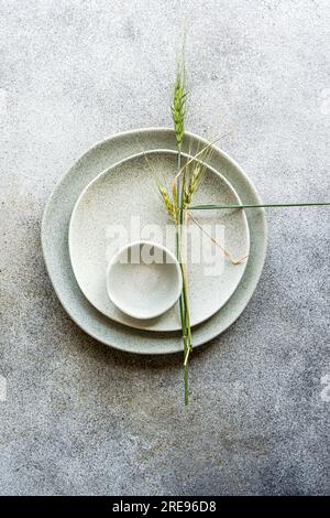 Dall'alto un elegante set di piatti in ceramica bianca con spighe di fondo grigio grano secco Foto Stock