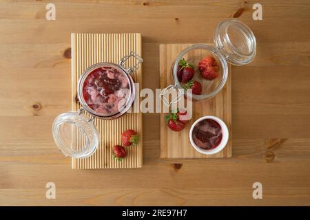 Dall'alto del vaso di vetro riempito di fragole fresche e frutta posta su un tavolino di legno sopra il tavolo alla luce del giorno Foto Stock