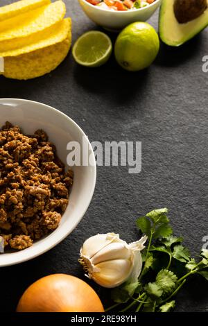 Vista ad alto angolo di tortilla, carne, avocado, limone, coriandolo, pomodoro e aglio sul tavolo Foto Stock