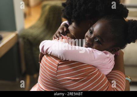 Felice madre e figlia afroamericana che si abbracciano prima della scuola a casa Foto Stock