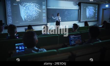 Giovane insegnante femminile che tiene una lezione di scienza dei dati a diversi gruppi multietnici di studenti femminili e maschili nella Dark College Room. Proiezione di una presentazione Foto Stock