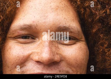 Ritratto ravvicinato di un uomo birazziale felice con capelli ricci rossi e lentiggini sorridenti Foto Stock