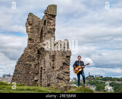 Il musicista dei Lonely Together Mike Baillie suona la chitarra presso le rovine della St Anthony's Chapel, Holyrood Park, Edimburgo, cotland, Regno Unito Foto Stock