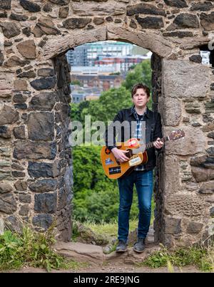 Il musicista dei Lonely Together Mike Baillie suona la chitarra presso le rovine della St Anthony's Chapel, Holyrood Park, Edimburgo, cotland, Regno Unito Foto Stock