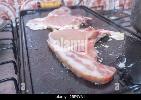 Bistecca di maiale su un barbecue fatto in casa che è sopra un fornello, concetto di preparare il cibo a casa. Foto Stock