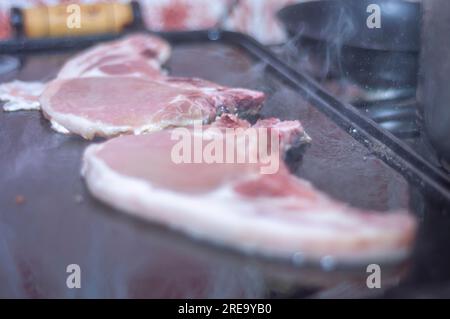 Bistecca di maiale su un barbecue fatto in casa che è sopra un fornello, concetto di preparare il cibo a casa. Foto Stock