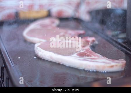 Bistecca di maiale su un barbecue fatto in casa che è sopra un fornello, concetto di preparare il cibo a casa. Foto Stock