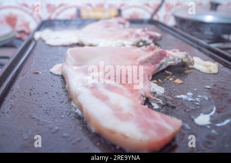 Bistecca di maiale su un barbecue fatto in casa che è sopra un fornello, concetto di preparare il cibo a casa. Foto Stock