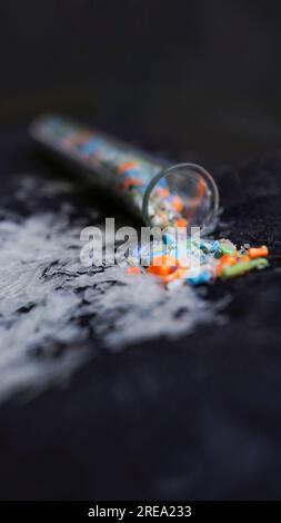 Macro-shot vettoriale di una provetta piena di microplastiche raccolte dalla spiaggia. Concetto di inquinamento idrico e gestione dei rifiuti industriali. Foto Stock