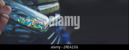 Foto macro di una provetta piena di microplastiche raccolte dalla spiaggia. Concetto di inquinamento idrico e gestione dei rifiuti industriali. Foto Stock