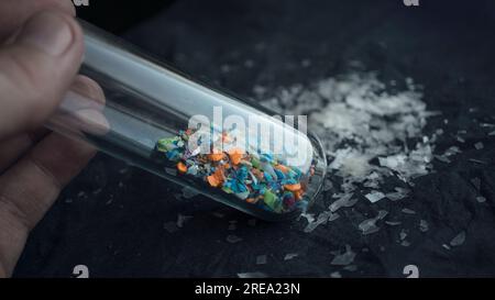 Foto macro di una provetta piena di microplastiche raccolte dalla spiaggia. Concetto di inquinamento idrico e gestione dei rifiuti industriali. Foto Stock