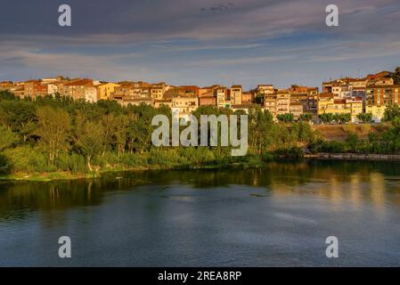 Villaggio di Flix sulle rive del fiume Ebro, visto dalla diga artificiale di Flix al tramonto (Ribera d'Ebre, Tarragona, Catalogna, Spagna) Foto Stock