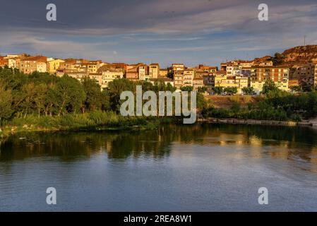 Villaggio di Flix sulle rive del fiume Ebro, visto dalla diga artificiale di Flix al tramonto (Ribera d'Ebre, Tarragona, Catalogna, Spagna) Foto Stock