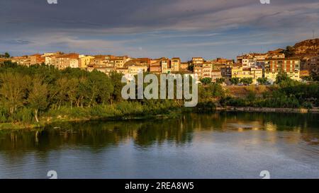 Villaggio di Flix sulle rive del fiume Ebro, visto dalla diga artificiale di Flix al tramonto (Ribera d'Ebre, Tarragona, Catalogna, Spagna) Foto Stock