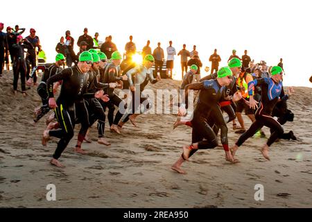 Huntington Beach, California, USA. 21 aprile 2018. Mentre gli spettatori osservano l'alba, determinati nuotatori multirazziali e bagnati hanno corso lungo una pista su una spiaggia sabbiosa per iniziare la parte di un evento di triathlon a Newport Beach, CALIFORNIA. (Immagine di credito: © Spencer Grant/ZUMA Press Wire) SOLO USO EDITORIALE! Non per USO commerciale! Foto Stock