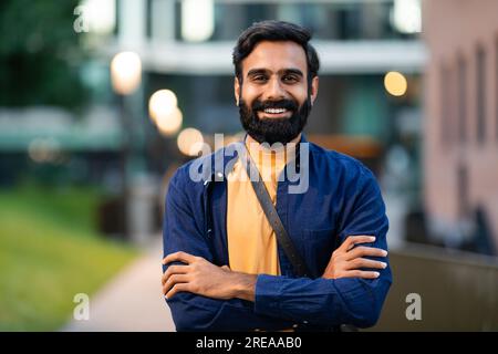 Ritratto di un allegro uomo arabo barbuto che posa in città Foto Stock