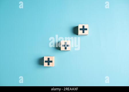 Icona Plus su blocchi di legno per concetto di medicina e assistenza sanitaria, accesso al benessere sanitario, persone con assistenza sanitaria, assicurazione sanitaria, vita familiare Foto Stock