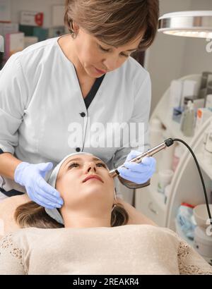 Trattamento viso ringiovanente presso la spa Salon Clinic. Giovane bella donna che riceve sollevamento anti-età, massaggio viso e cura della pelle Foto Stock