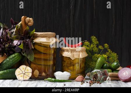 Cetrioli in scatola in vasetti, insalata di cetrioli sottaceto, cetriolini freschi, verdure, spezie ed erbe per la marinata. Ingredienti per l'inscatolamento domestico. Foto Stock