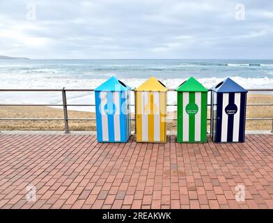 Contenitori colorati per il riciclaggio in spiaggia, con istruzioni per la gestione dei rifiuti in inglese e spagnolo. Foto Stock