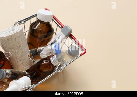 Mini carrello con diversi farmaci su sfondo beige Foto Stock