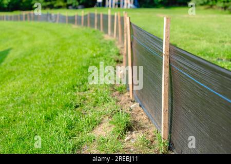 Tessuto Silt Fence con pali in legno installati prima dell'inizio della costruzione. Foto Stock