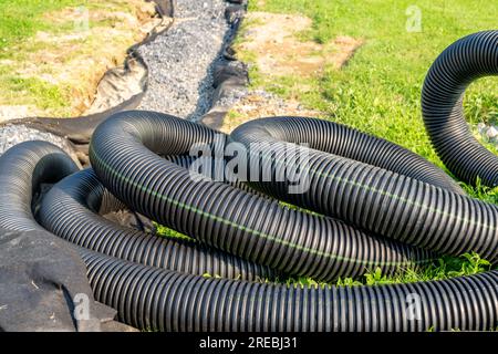 Tubo di scarico nero per acque piovane utilizzato per mitigare le acque sotterranee. Forma arrotondata astratta. Foto Stock