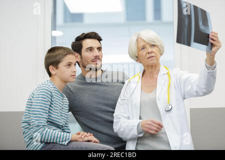 medico pediatra donna e ragazzo che guarda i raggi x Foto Stock