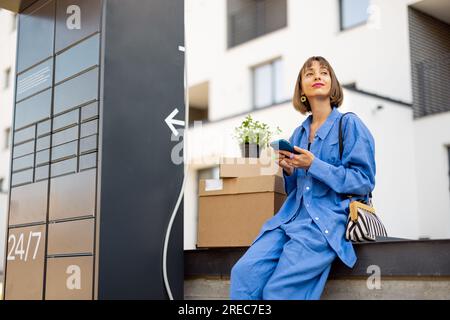 Donna con pacchi vicino alla macchina per ufficio postale all'aperto Foto Stock