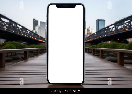 lo smartphone mostra uno schermo bianco posizionato su un tavolo bianco circondato dal paesaggio cittadino. Smartphone Mockup Blank Foto Stock
