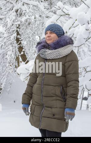 In inverno, una donna indossa caldi cappelli a maglia con giacca e guanti Foto Stock