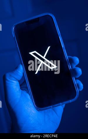 Telefono cellulare in una mano con il simbolo X, il nuovo nome della precedente app Twitter Foto Stock